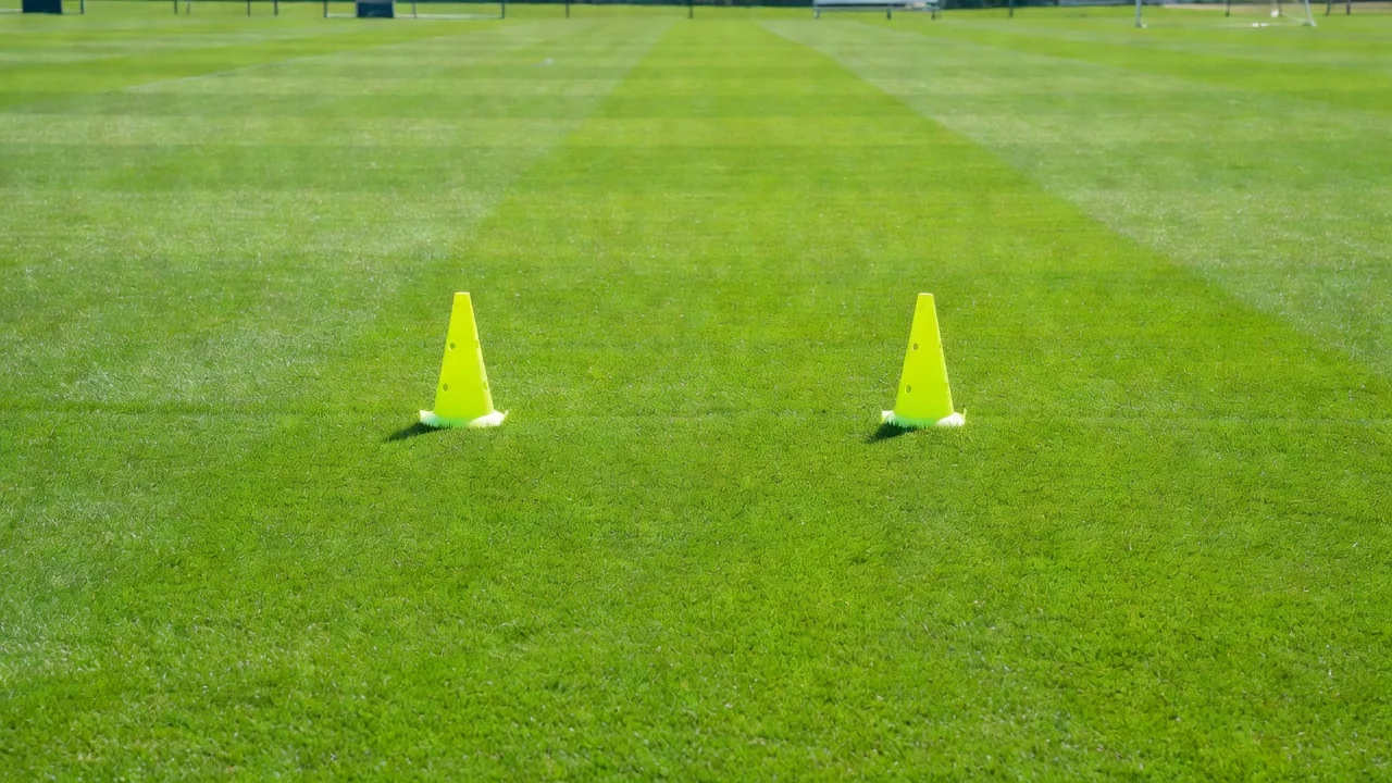 An empty centre-forward position marked by neon training cones on grass