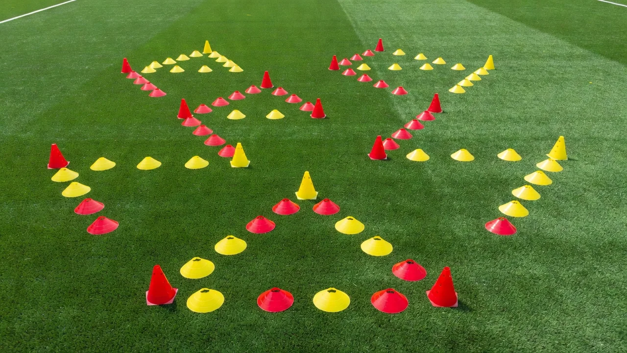 Aerial view of red and yellow cones forming triangular passing patterns on a bright pitch