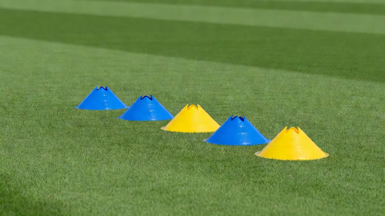 Three blue cones behind two yellow cones in a staggered line on bright grass